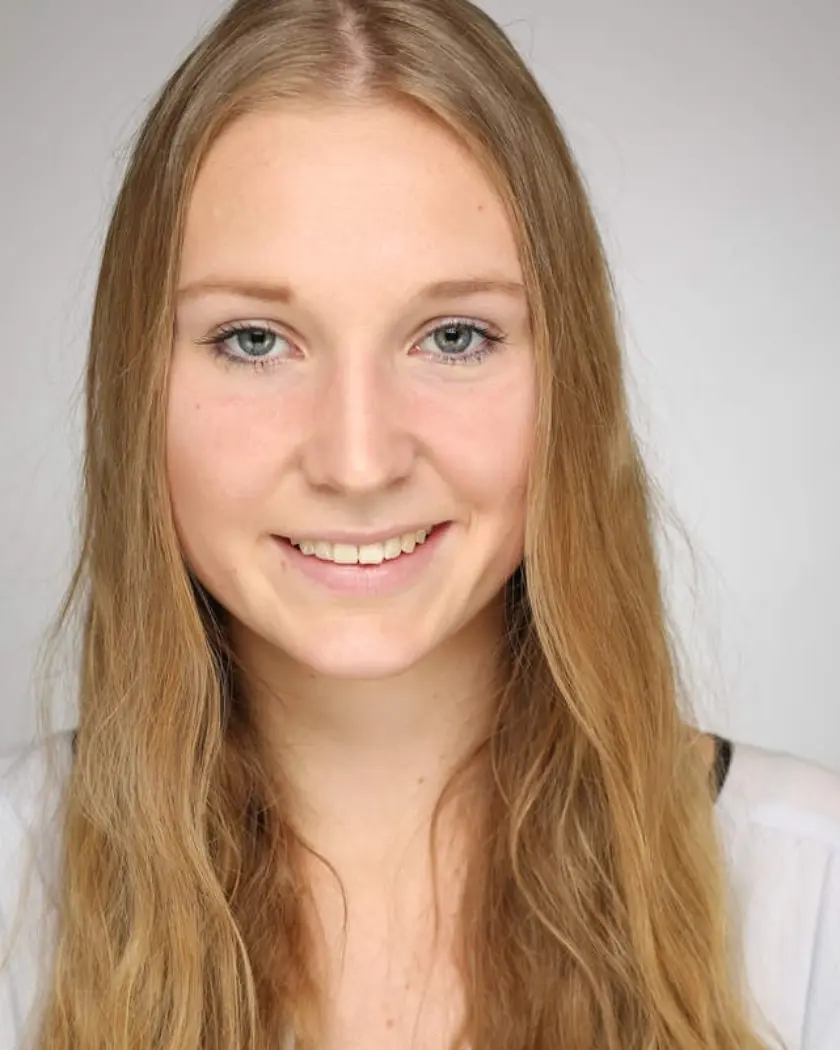 A young woman with long, straight blonde hair smiles warmly at the camera against a neutral background.